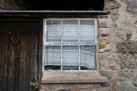 Vieille fenêtre à simple vitrage d'une passoire thermique, cible de remplacement de fenêtre